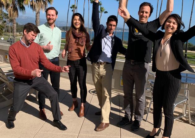 Group of six students cheering on patio overlooking ocean