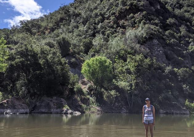 Woman in backpack standing in shallow river