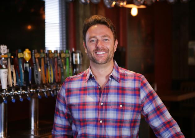 Smiling man in front of a beer tap