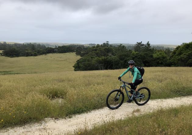 Woman riding bicycle on dirt trail 