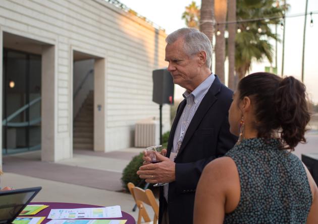 Woman talking to man and woman at a table with flyers