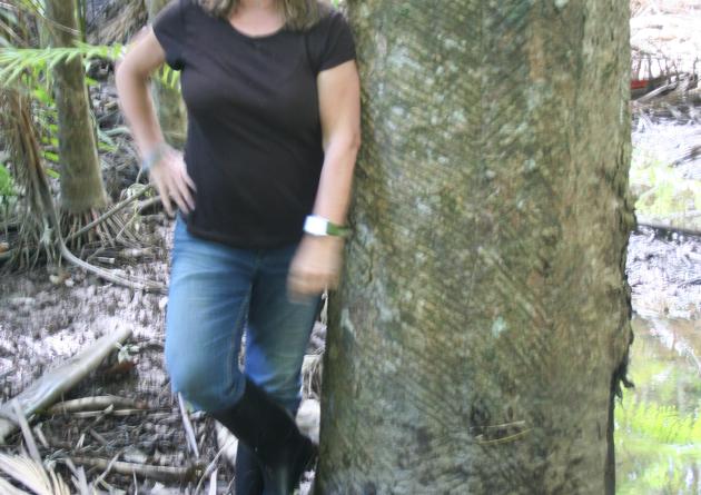 Susanna Hecht leans against a large tree trunk