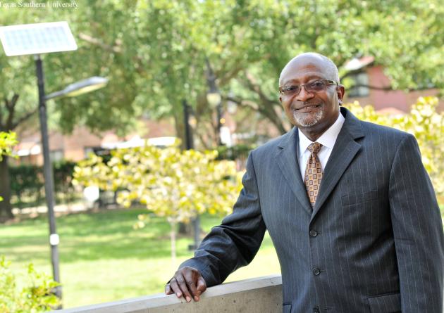 Robert Bullard stands with his hand on a railing in front of greenery