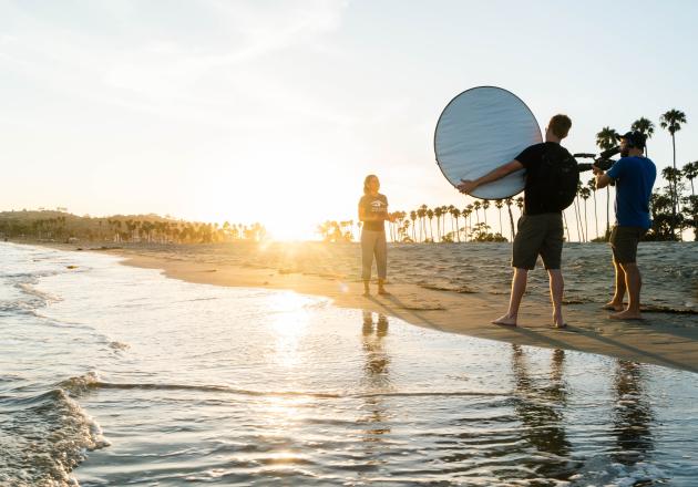 People on beach at sunset making a video