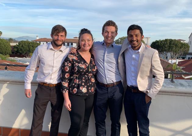 Group of four students pose together in celebration