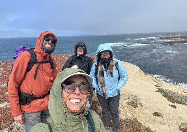 Four students stand on an ocean cliff