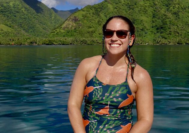 Erin Winslow sits in a boat in front of green mountains