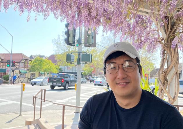 Seonghoon Kim sits under purple flowers