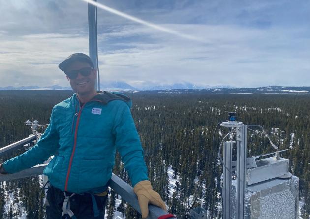 Troy Magney stands on a platform in the snow