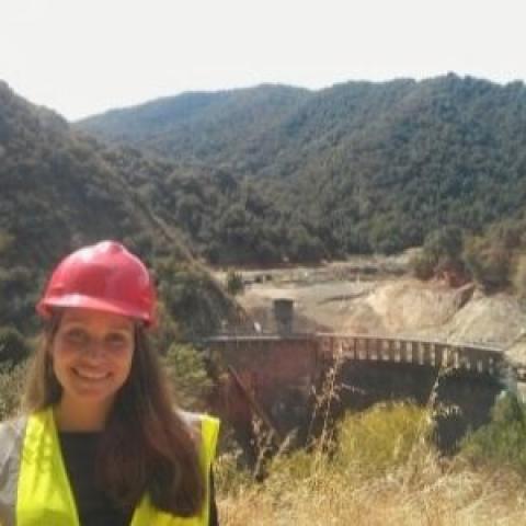 Woman in hardhat with San Clemente dam in background