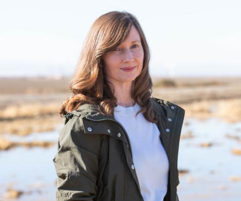 Ann Hayden stands outside near water