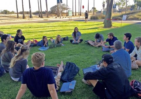 Group of students sitting in circle on grass