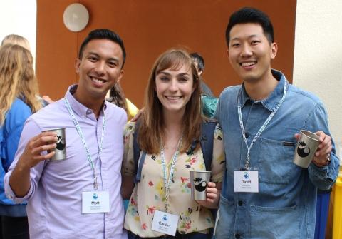 Three students smiling and holding up cups