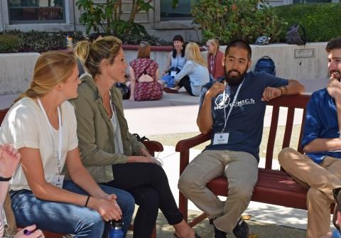 Group of students talking in courtyard sitting on benches