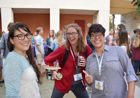 Three people pose together smiling