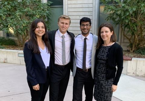 Two women and two men in suits stand together in courtyard