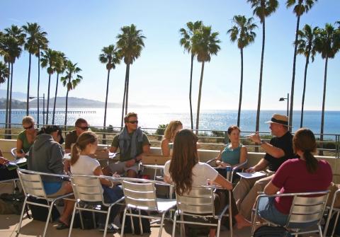 Class group listening to lecture sitting on sunny terrace