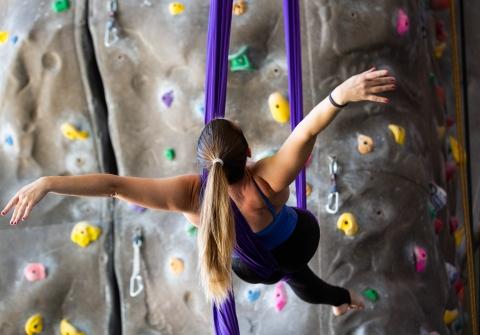 Woman does suspended acrobatics by climbing wall