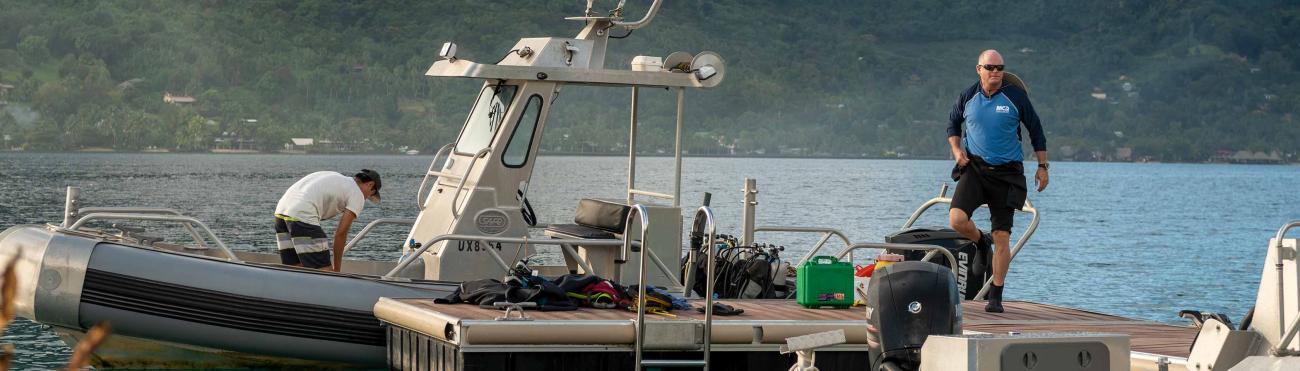 Two men gear up scuba equipment on a boat