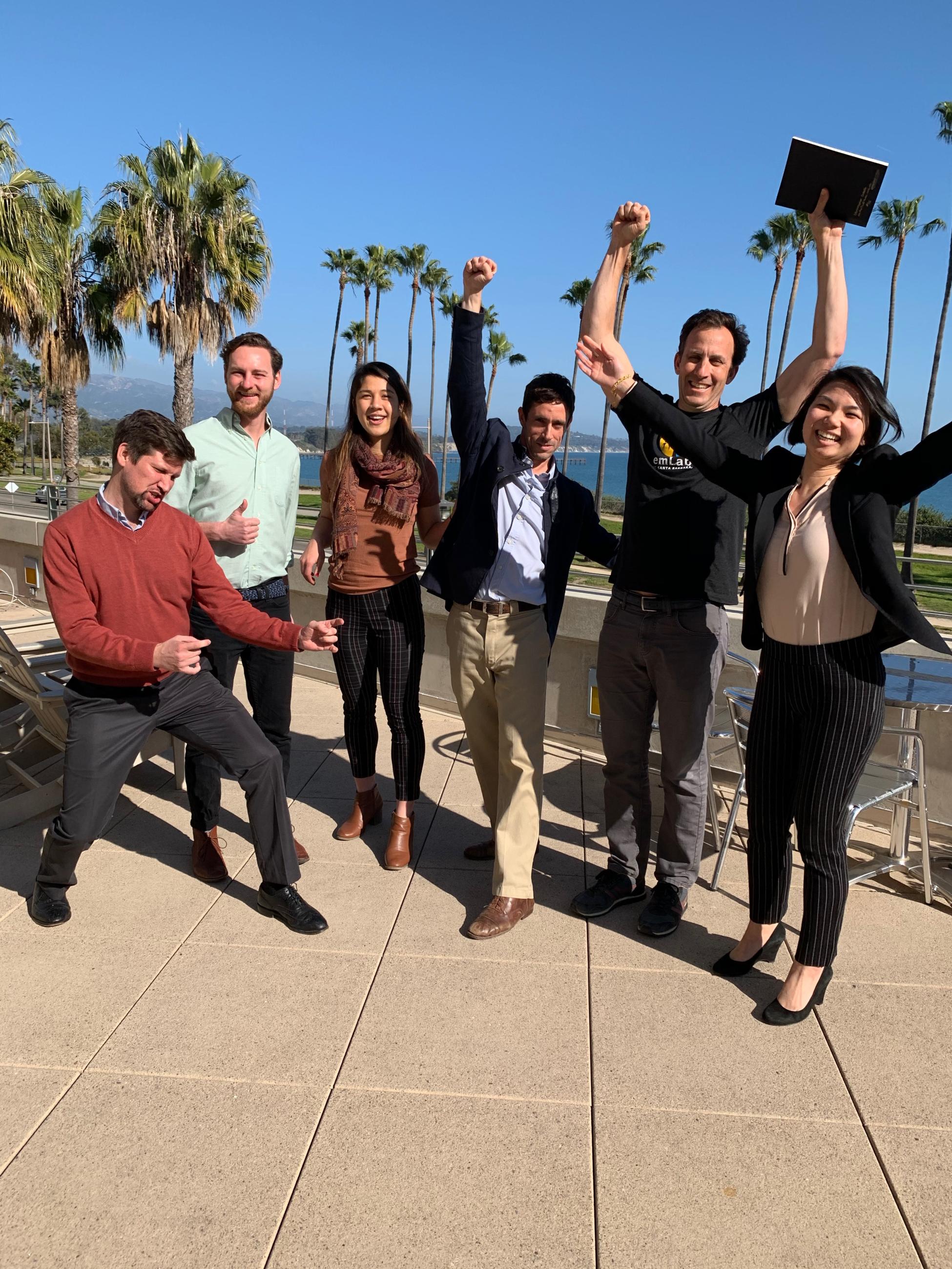 Six students cheering in happiness with ocean view