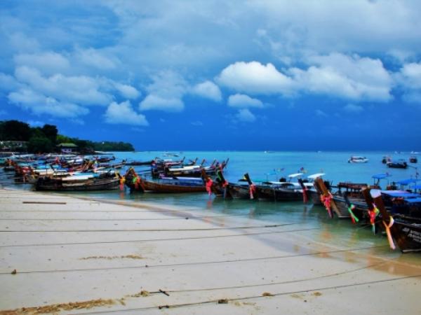 A line of fishing boats tethered to shore under a blue sky