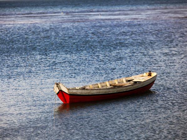 Small fishing boat floats unattended in ocean.