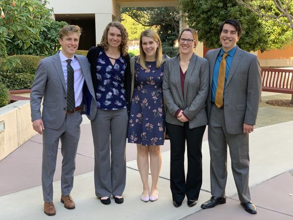 Group of five students in courtyard smiling