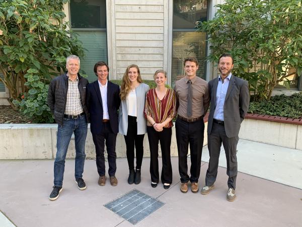 Five students stand with professor in group