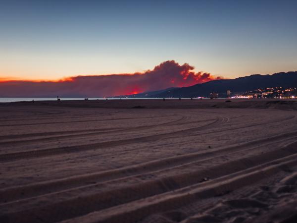 Wildfire smoke looms over hills of a seaside town