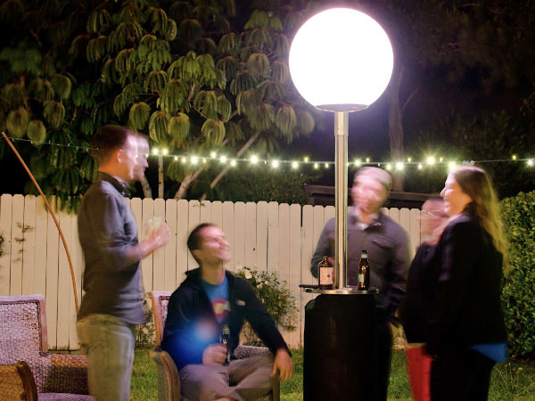 Four people sitting outdoors at night around a bright lamp