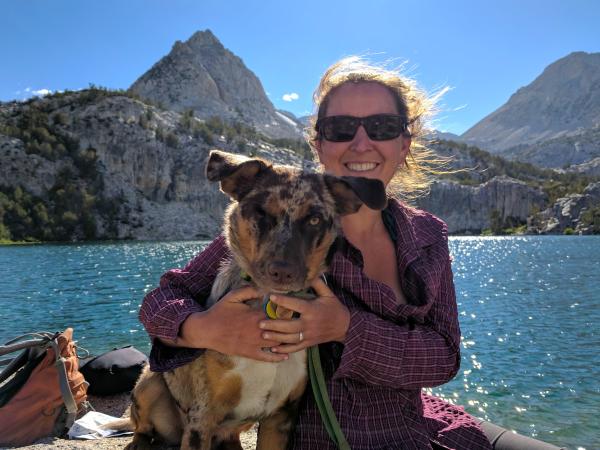 woman and dog sitting by a sparkling lake