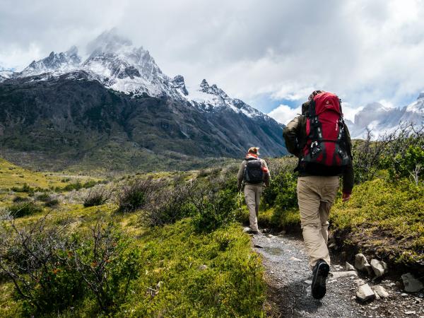 Woman and man hiking through valley, with snowcapped mountains.