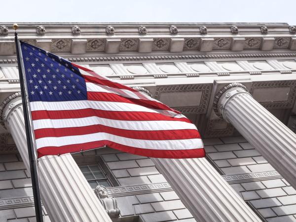 United States flag flies in front of a stately building