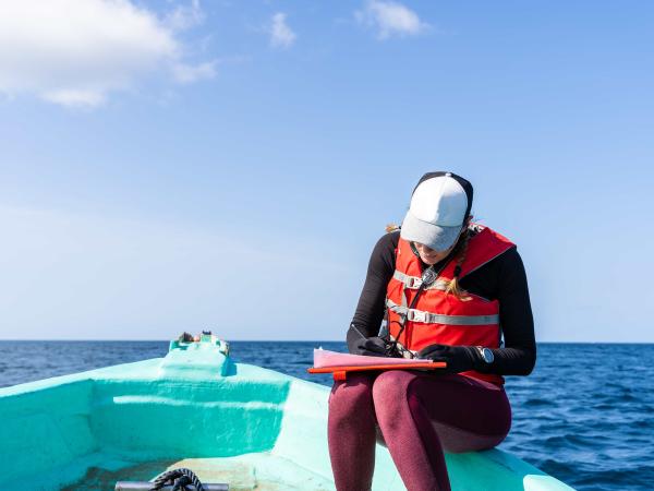 Marine biologist writing down data sitting on a boat