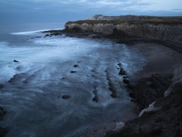 Coastal california scene with dark clouds, waves, rocky beach and cliffs