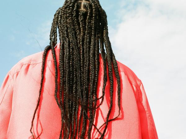 a person with braided hair looking up at the sky